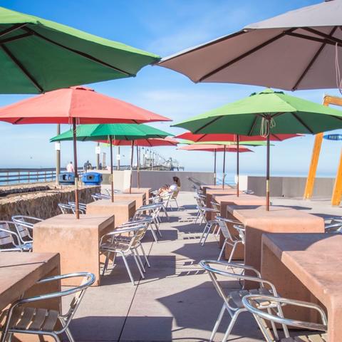 Tables with large umbrellas and chairs at Portwood Pier Plaza at the Port of San Diego