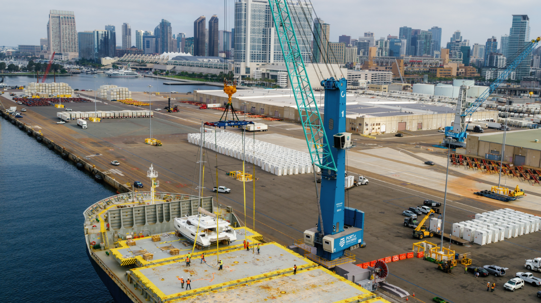 Aerial of the Port of San Diego's all electric mobile harbor crane lifting a yacht