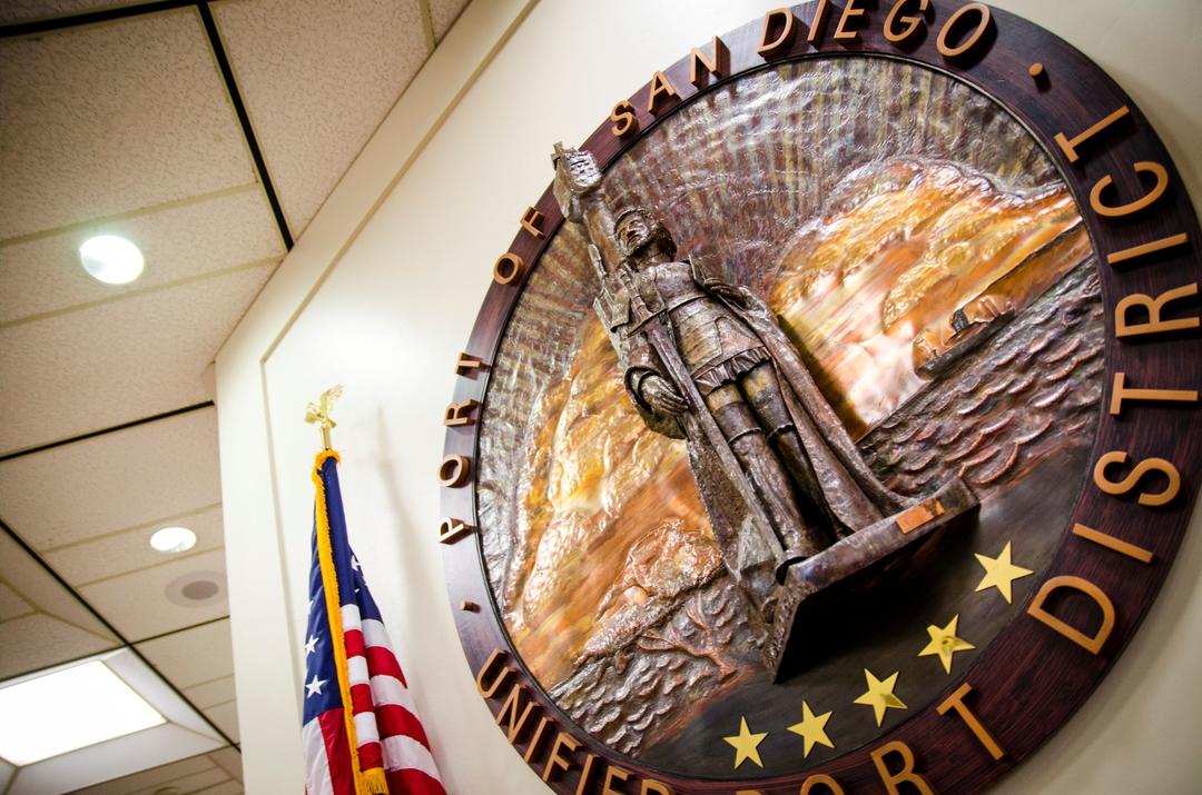 The round seal of the Port of San Diego hangs on a wall next to an American flag