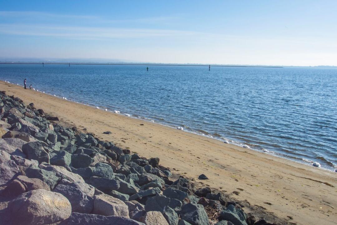 Shore rocks, sand, and water at Chula Vista Bayside Park at the Port of San Diego