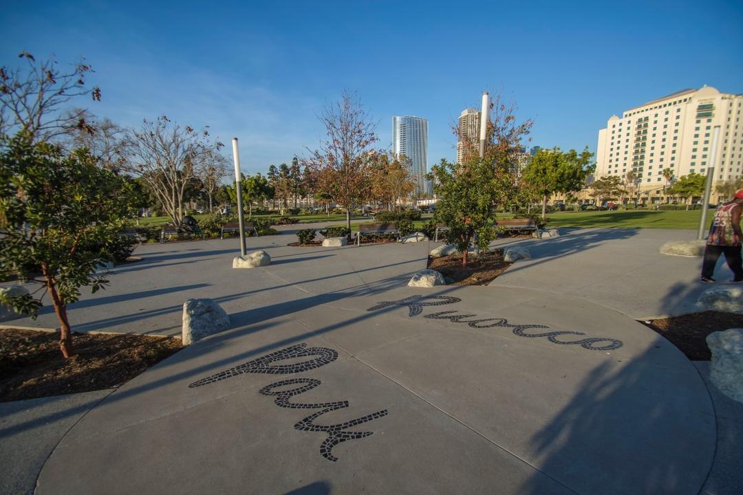 Landscaped walkway with trees, rocks, and tile mosaics at Ruocco Park at the Port of San Diego