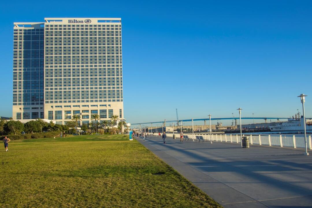View of Hilton hotel, San Diego-Coronado Bay Bridge, grass, and path at San Diego Bayfront Park at the Port of San Diego