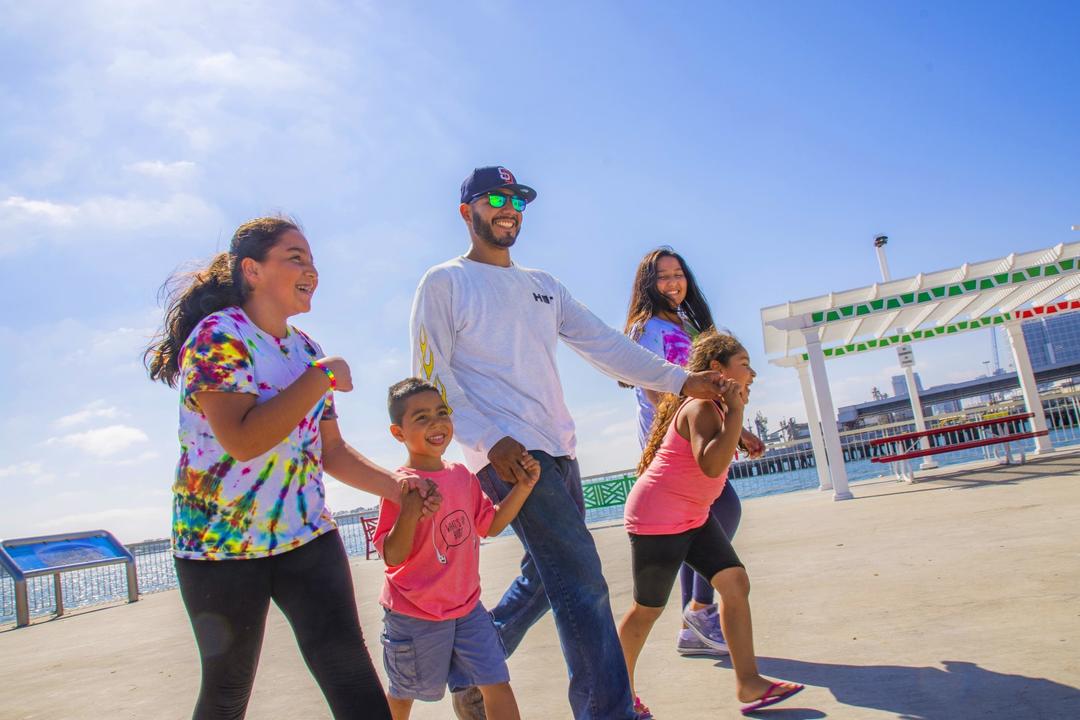 A family enjoys the sunshine on the pier at Cesar Chavez Park - Port of San Diego