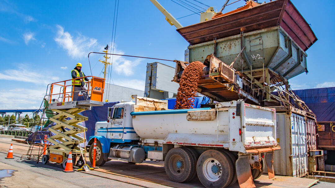 rust colored boxite being fed across a conveyor belt into a truck at the Port of San Diego Tenth Avenue marine Terminal
