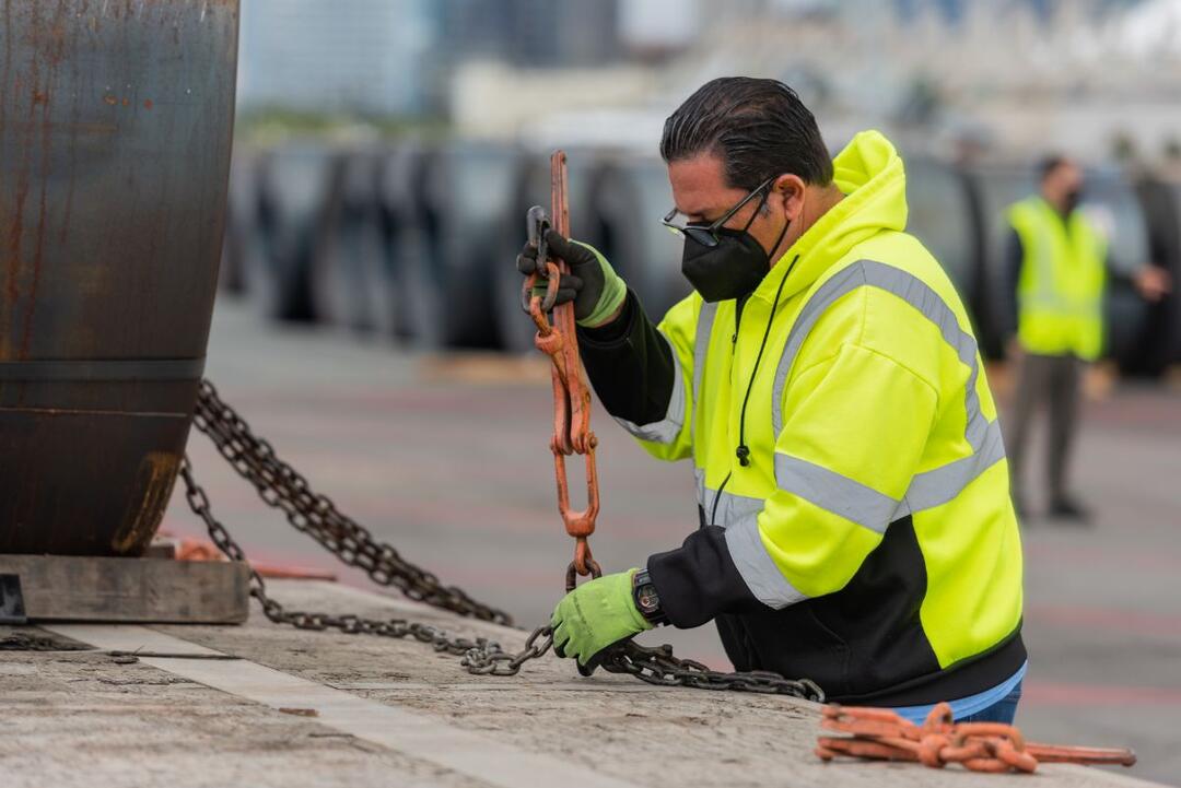 A man in a bright yellow jacket works with a chain