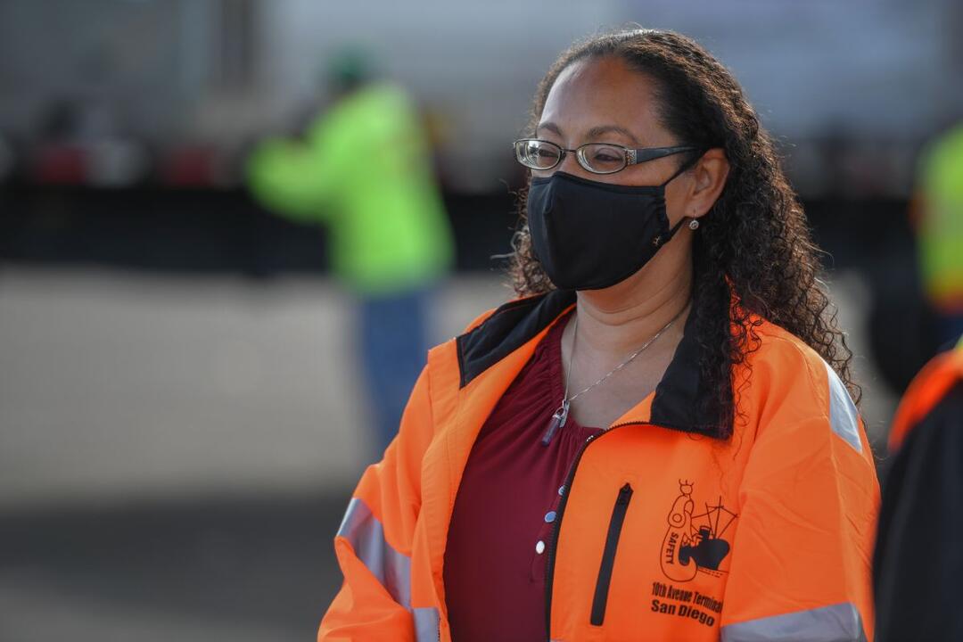 a woman in an orang jacket wearing a black mask