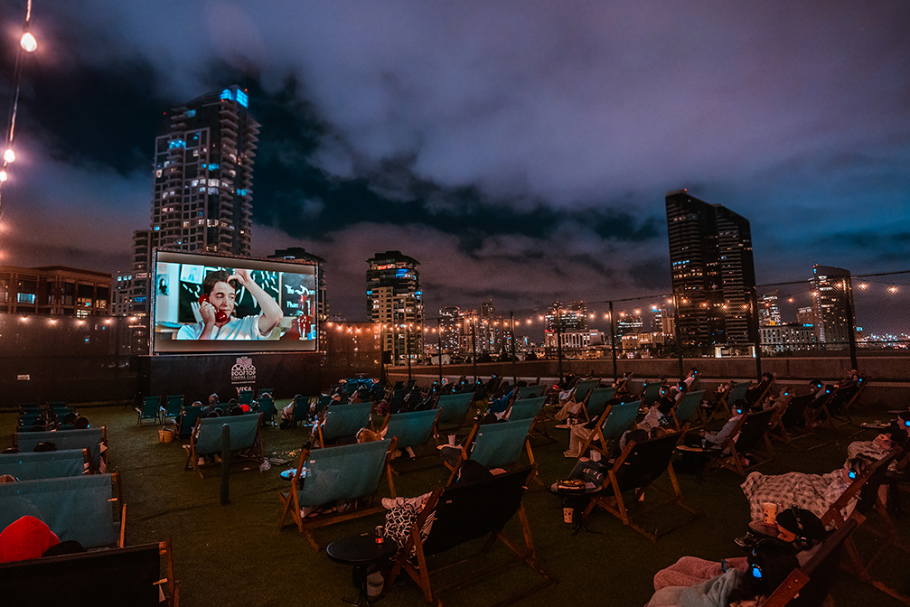 people in lounge chairs watch a movie on a roof