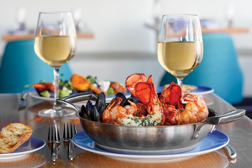 two glasses of wine sit behind a bowl of shrimp