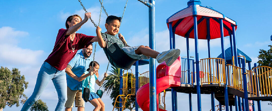 Mother pushing son in swing at Pepper Park