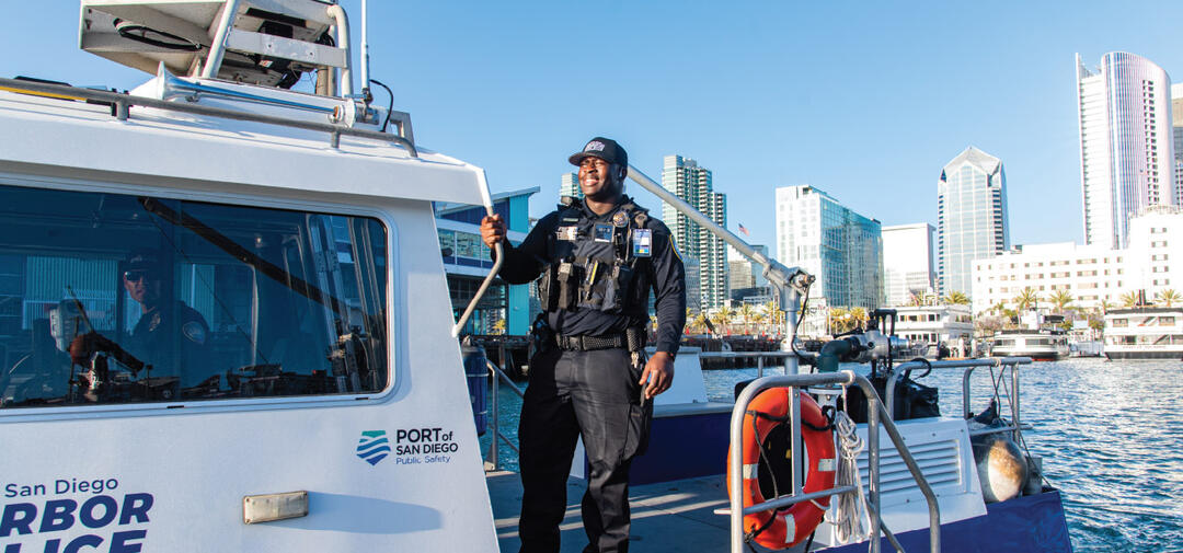 a man in uniform stands on a police boat in San Diego Bay. 