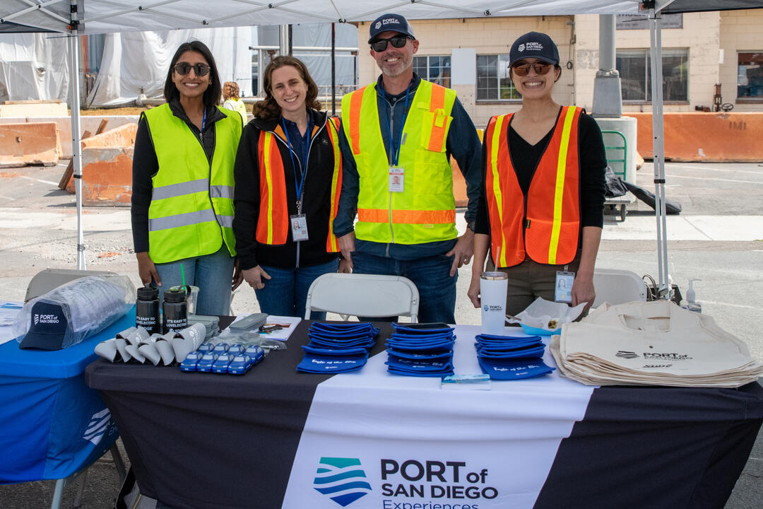 four Port team members smile at you while running a community outreach event