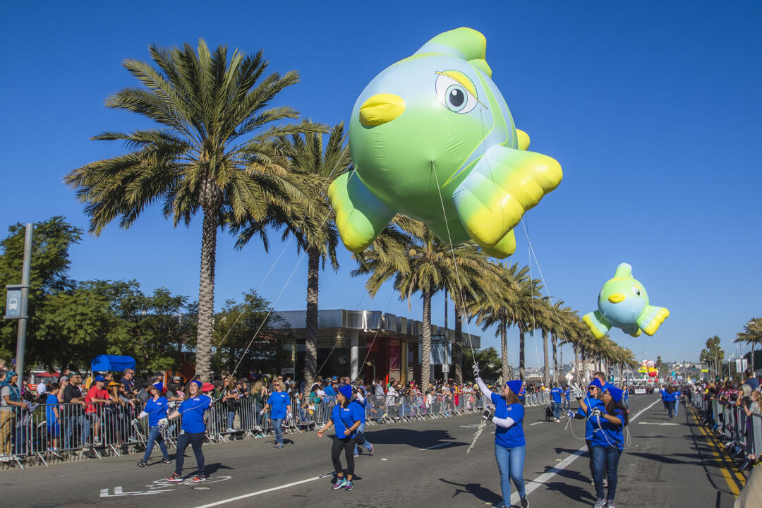 Image of green, blue and yellow parade balloon in the shape of a fish at the 2017 Holiday Bowl Parade