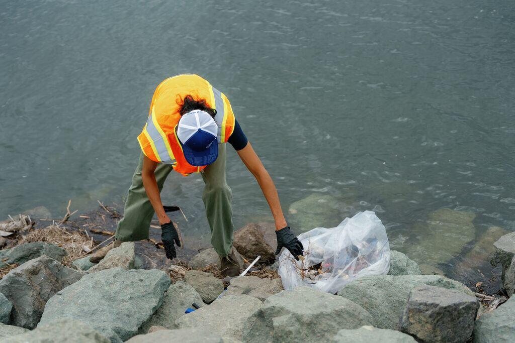 Person picking up trash by water