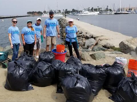 People with trash bags by San Diego Bay. 