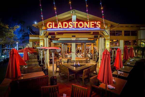 Exterior of Gladstone's restaurant with neon sign and exterior patio.