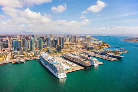 Three cruise ships with the city skyline behind them.