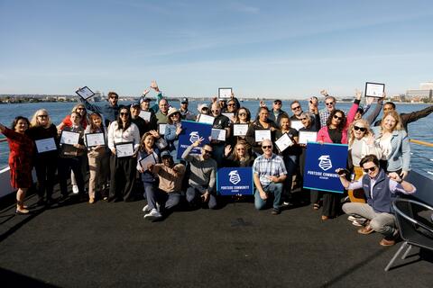 Photo of graduates and Port staff on a boat on San Diego Bay for the graduation of the first cohort of the Port of San Diego's first cohort of the Portside Community Academy in December 2023. The backdrop is blue sky and blue water.