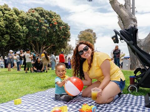Woman and child sitting on picnic blanket outside