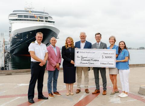 Group of people with check and cruise ship behind them