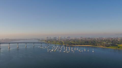 Aerial drone image of San Diego Bay taken from Tenth Avenue Marine Terminal looking southwest. Blue water, Coronado Bridge, and Coronado in view.