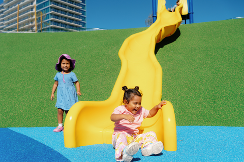 Two children sitting near playground slide at Harbor Park Playground in Chula Vista