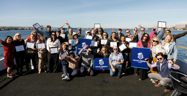 Photo of graduates and Port staff on a boat on San Diego Bay for the graduation of the first cohort of the Port of San Diego's first cohort of the Portside Community Academy in December 2023. The backdrop is blue sky and blue water.