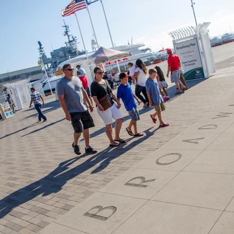 A family walks along Broadway Plaza at the Port Pavilion Broadway Pier Port of San Diego