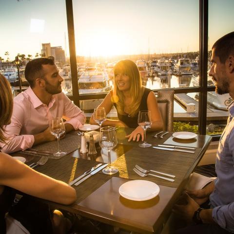 four adults enjoying a sunset dinner on Harbor Island Port of San Diego