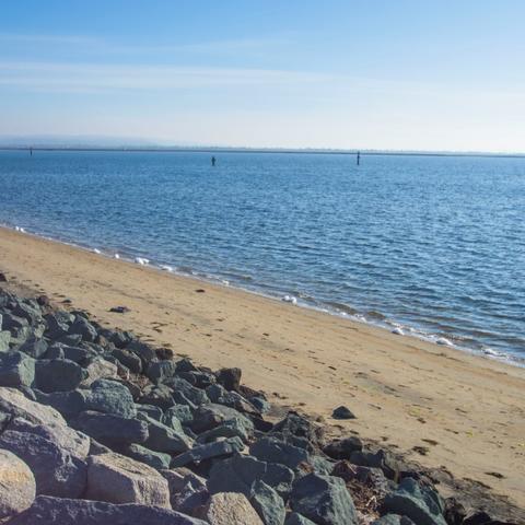 Shore rocks, sand, and water at Chula Vista Bayside Park at the Port of San Diego