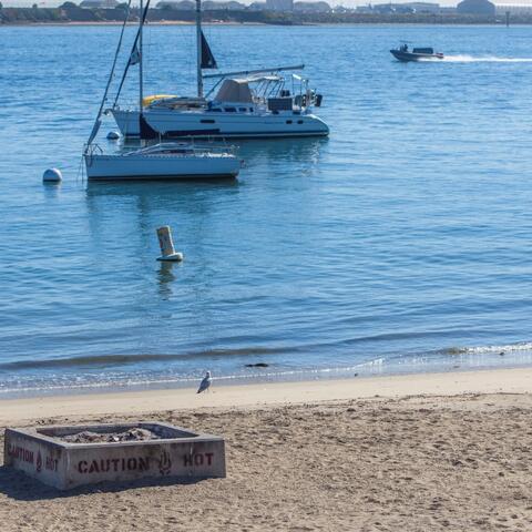 Boats on the water and fire ring on the beach shore at Shelter Island Shoreline Park at the Port of San Diego