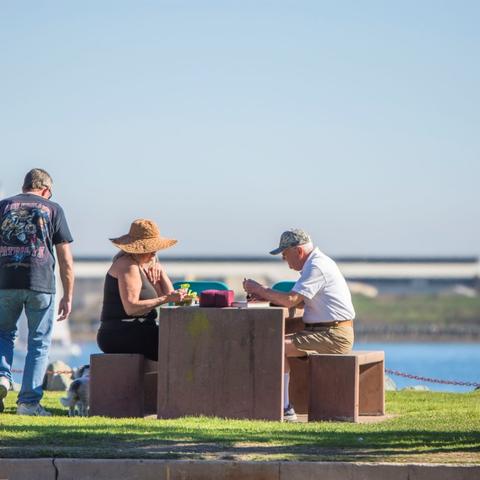 People enjoying lunch at the picnic table overlooking the water at Shelter Island Shoreline Park at the Port of San Diego