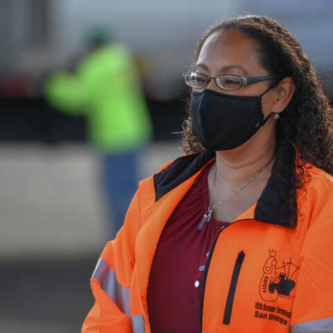 a woman in an orang jacket wearing a black mask
