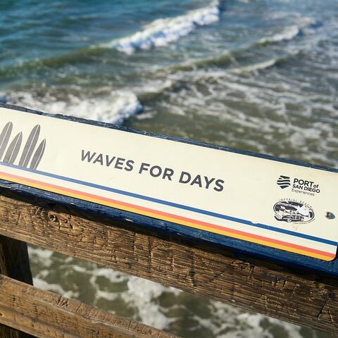 White sign on the IB Pier says "Waves for Days"