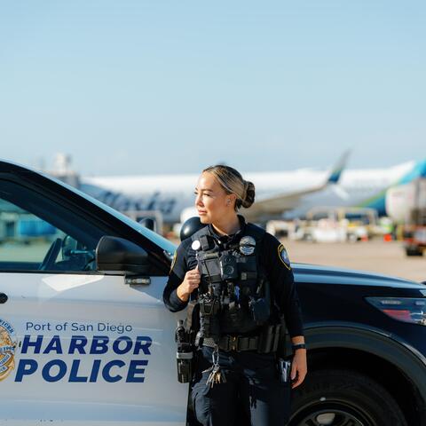 A Harbor Police Officer stands in front of her patrol car at the airport